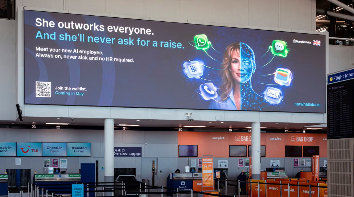 Airport billboard advertising an AI Assistant who "outworks everyone and never asks for a raise"